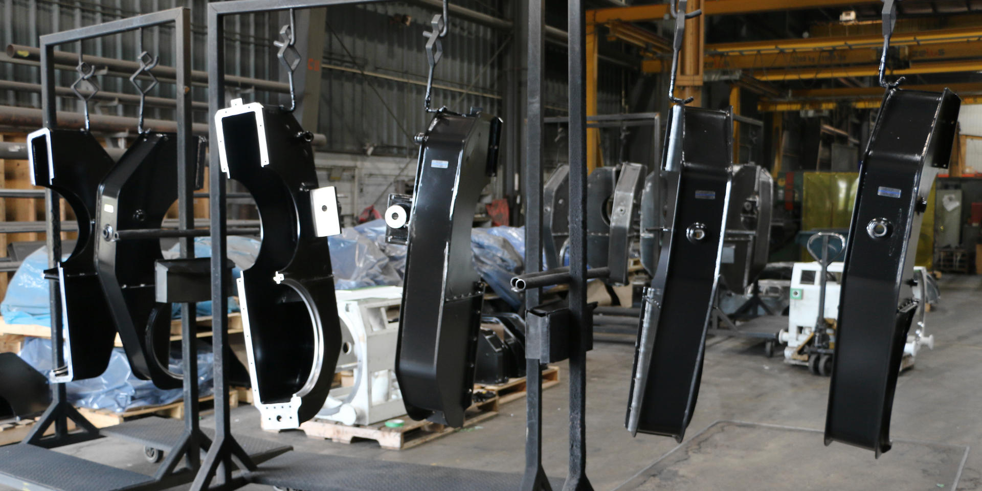 Painted gear cases hanging for drying in paint booth area before having final inspection completed at Piper Lane location. This photo and others in this slideshow demonstrate ADJ Industries' painting capabilities.